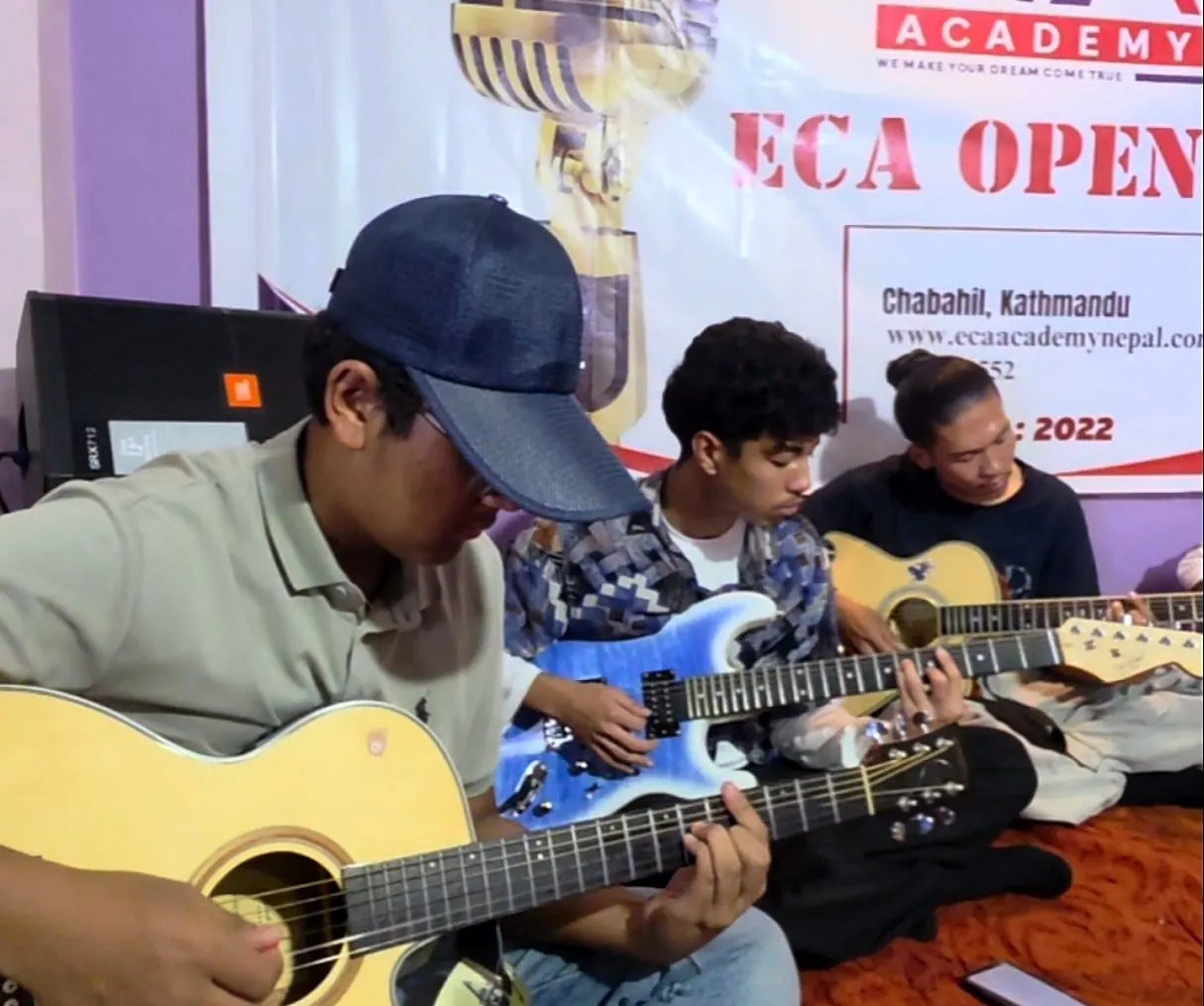 Students playing guitars on stage at ECA Open Mic